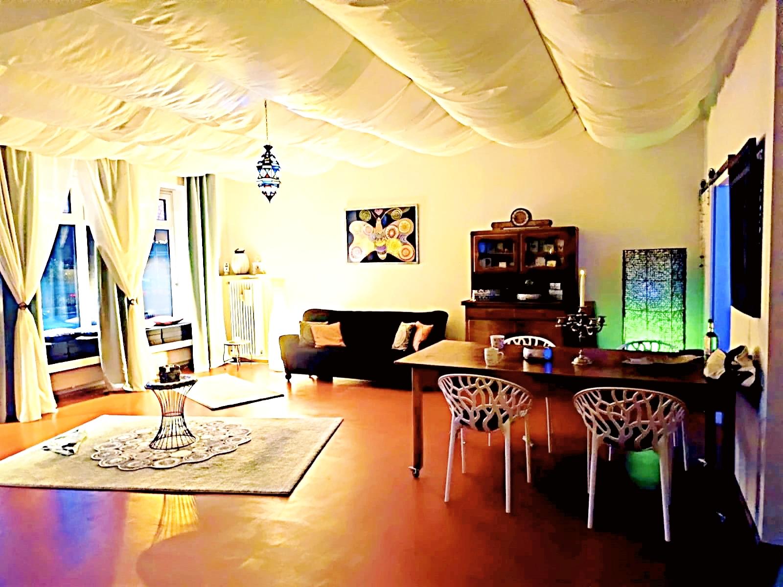 Der Therapieraum, diffus beleuchtet, ein Tisch mit Stühlen, ein Sofa und ein älterer Schrank erzeugen eine warme, ruhige Atmosphäre